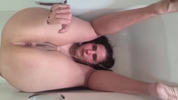 Piss whore pissing over her face in the bathtub